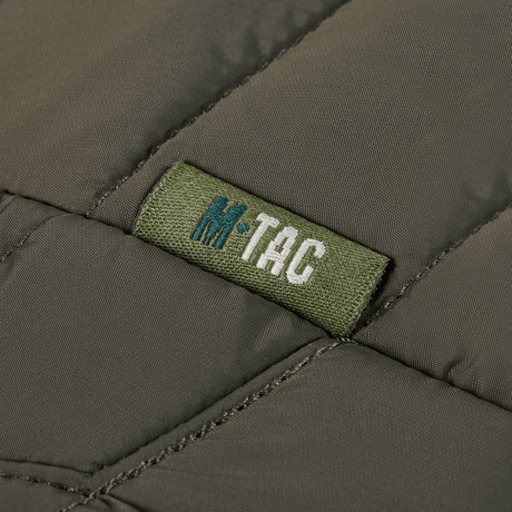 Detalje af M-Tac Damevest Primaloft med slidstærkt vandafvisende yderstof. Fokus på M-Tac logoet og den tekniske kvalitet.