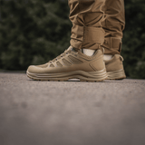 Person iført M-Tac Tactical Sneakers IVA til udendørs aktiviteter, lette og ventilerede sko ideelle til trekking og hverdag.