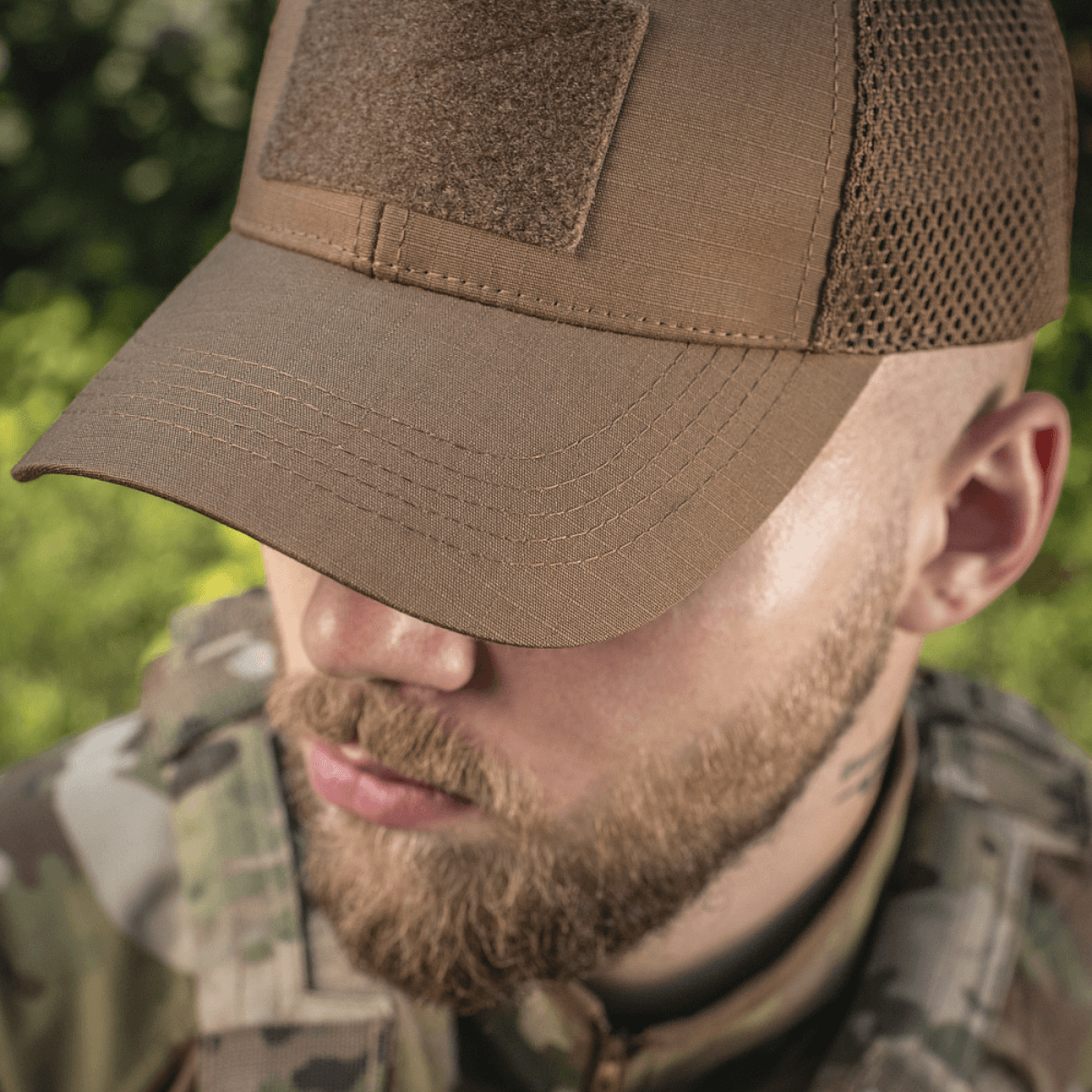 M-Tac Baseball Cap Ripstop Elite Flex i brun med netpaneler, båret af en person i camouflage-tøj, set forfra udendørs.