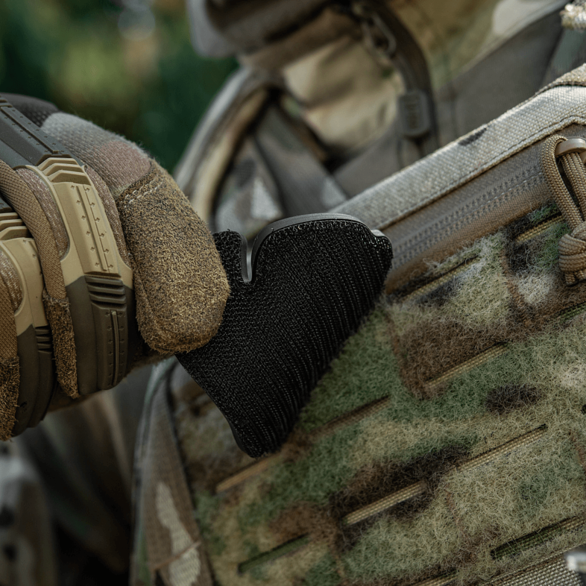 Taktisk handske justerer sort velcro-patch på camouflagedragt udendørs