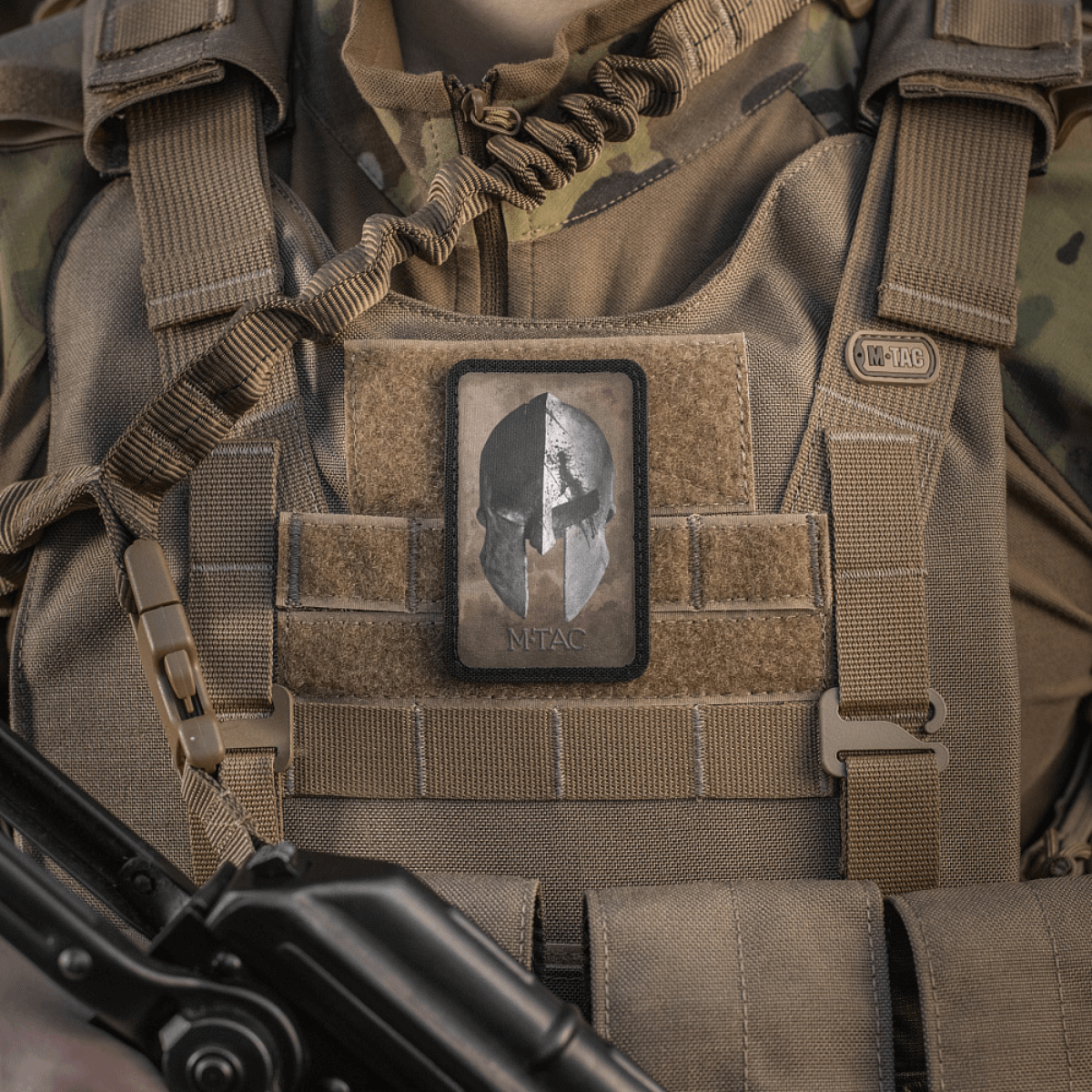M-Tac Spartan Hjelm Patch på militær vest, symboliserer mod og styrke, lavet af slidstærk Cordura 500D med Velcro fastgørelse.