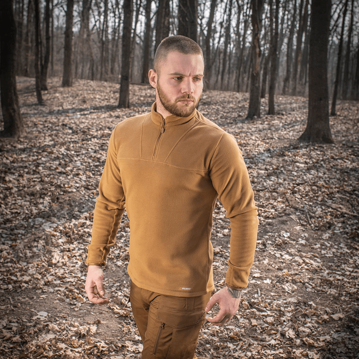 Mand iført M-Tac Delta Polartec Fleecejakke i skoven, sepiafarvet fleece, halv lynlåslukning, bæredygtig konstruktion, åndbart design