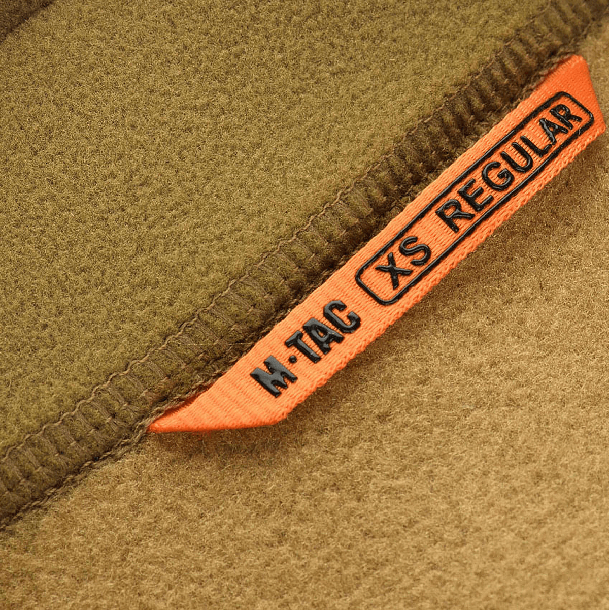 Nærbillede af M-Tac Polartec Sport Fleecejakke med etikette "XS Regular"