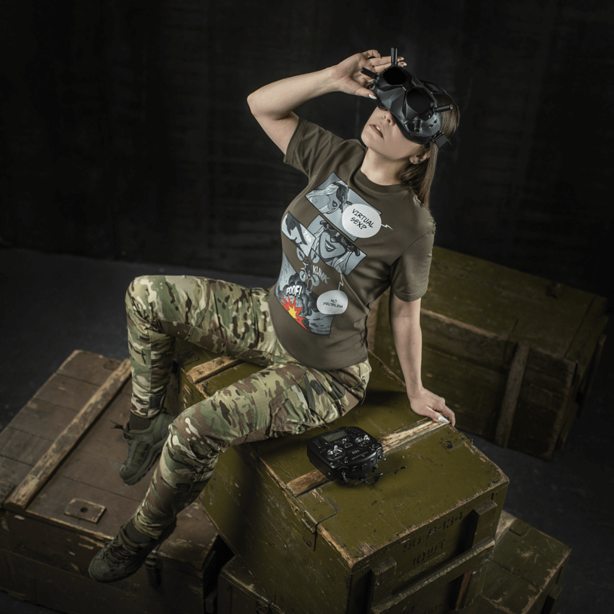 Kvinde iklædt M-Tac T-Shirt Comics Drone Girl med dronecontroller, symboliserer styrke og præcision.