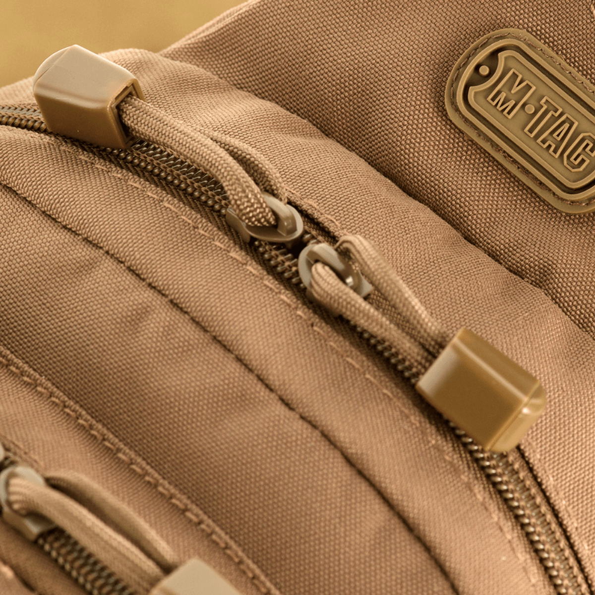 Nærbillede af M-Tac Assistant Taske med lynlåse og logo, enkeltseler-rygsæk med MOLLE-paneler og justerbar strop til daglig brug.