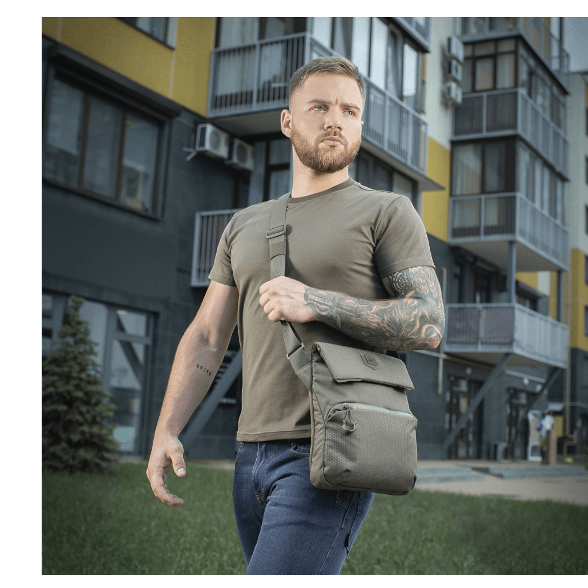 Mand med M-Tac Konvert Taske Elite i gråt bymiljø, bærende en moderne tablet-design taske lavet af holdbart Cordura materiale.