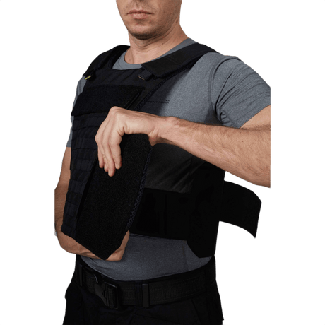 Mand iført Anorak Niobium® Duty III-M Stik & Skudsikker Vest, justerer vesten for optimal beskyttelse og komfort.