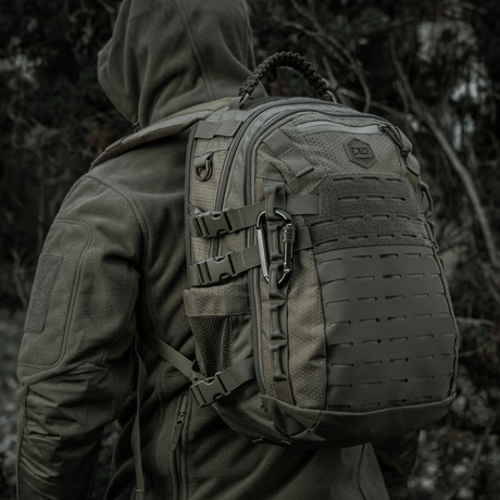 Rygsæk med M-Tac Karabinhage 10 cm i militært udstyr, fremstillet af 40Cr legeret stål, vist i udendørs skovmiljø.