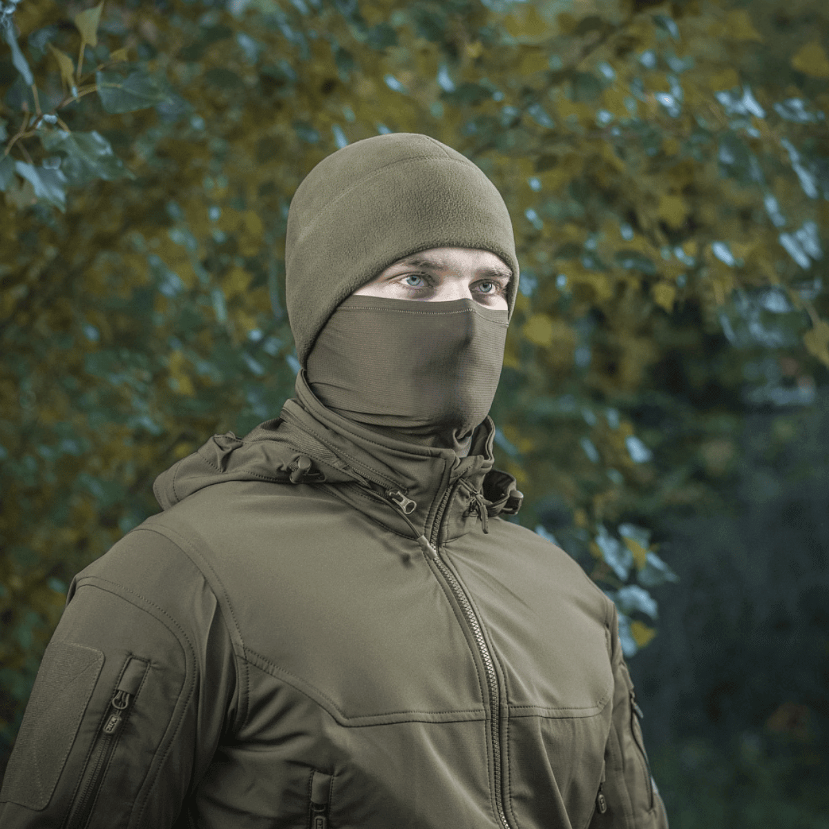 Mand iført M-Tac Polartec Vent Tube Scarf, der fungerer som ansigtsmaske, omgivet af efterårsblade.