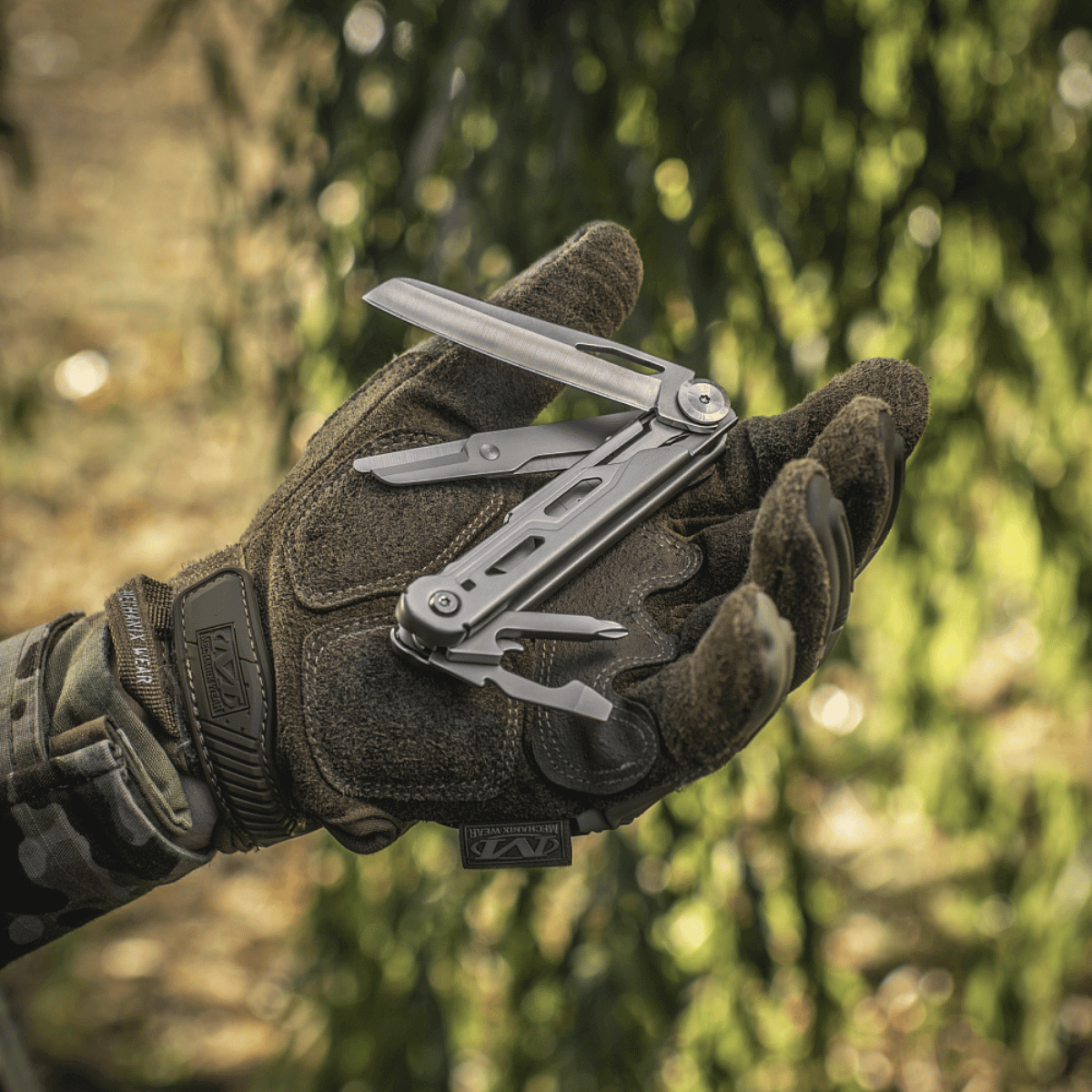 M-Tac Type 3 Foldekniv (5-i-1) Rustfrit Stål i hånden på en person udendørs, viser multiværktøjet med fem funktioner.