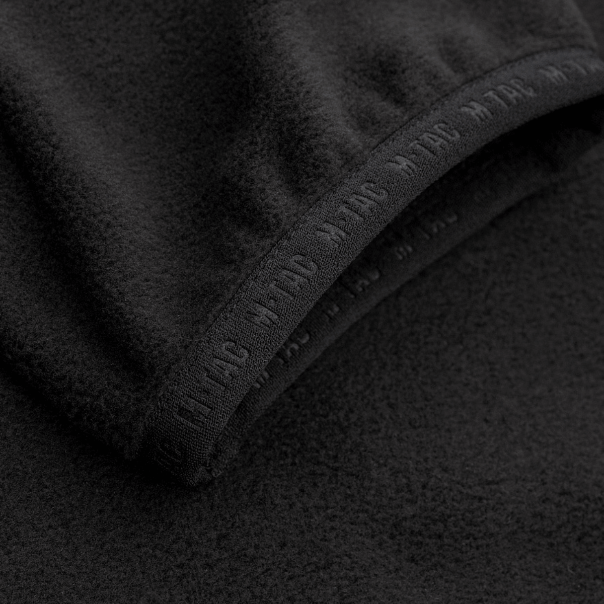 M-Tac Delta Fleece Jakke detaljer med tommelhuller, komfortabelt design og varm fleece, ideel til aktiv brug og kolde vejrforhold.