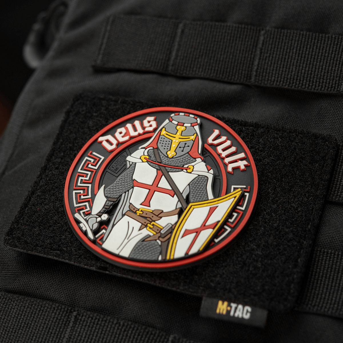 M-Tac Deus Vult 3D PVC Patch på en sort taske, viser en ridder med teksten 'Deus Vult', fastgjort med Velcro. Ideel til outdoor brug.