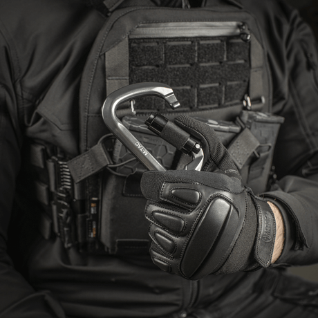 M-Tac Key-Lock Karabinhage af aluminium, egnet til klatring og sikkerhed, holdt af en person i taktisk udstyr.