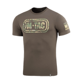 M-Tac T-Shirt Logo med camouflage mønster, ikonisk M-Tac-logo og slogan, "Born by Revolution – Hardened by War" på ærmet.