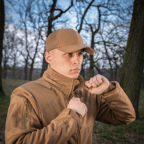 Mand iført M-Tac Mesh Flex Ripstop Baseball Cap i en skov, viser praktisk og holdbar sørge for komfort og ventilation til udendørs aktiviteter.