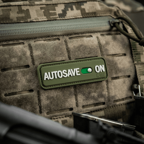 M-Tac Patch Autosave PVC 3D morale patch på en camouflage rygsæk, lavet af PVC, 8 x 2.5 cm, med fuld farve og velcro bagside.