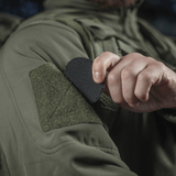 Person fastgør M-Tac Patch Operator 3D PVC med Velcro på jakke, taktisk design, morale patch, 6x7 cm, lavet af PVC.