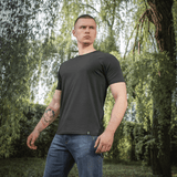 Mand iført M-Tac Raglan T-Shirt 93/7 foran grøn baggrund, materiale 93% bomuld 7% elastan, stilfuld og åndbar t-shirt i sort.