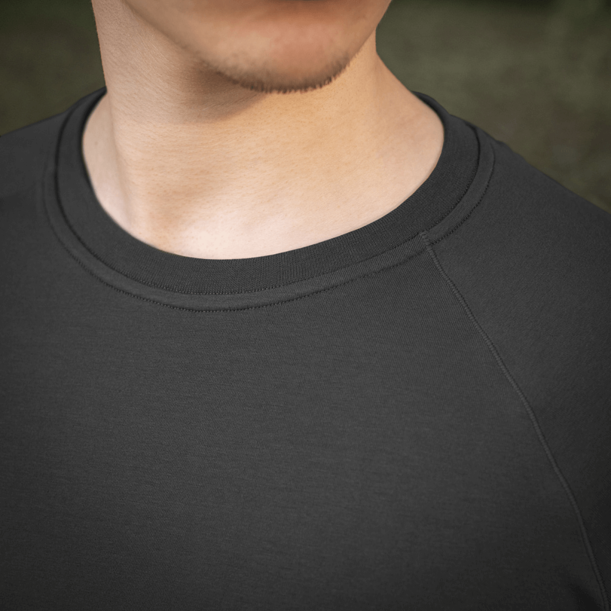 Nærfoto af en person iført en M-Tac Raglan T-Shirt 93/7 med åndbarhed og komfort i fokus