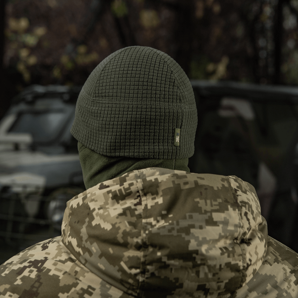 Person iført M-Tac Rip-Stop Fleece Hjelmliner, kamuflagejakke i udendørs miljø