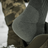 M-Tac Sokker Mid Calf Mk.4 i brug med polstrede områder til beskyttelse under trekking, fremhæver termozoner og fodbue-støtte.