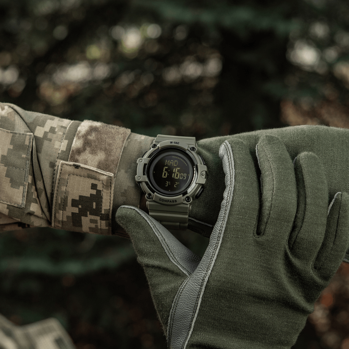 M-Tac Tactical Ur med Kompas 2233 båret af soldat udendørs, viser robust design og funktioner som LED-belysning og 5ATM vandmodstand.