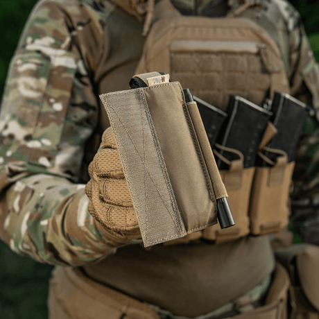 M‑Tac Tourniquet Pouch Elastic Gen.5 holdt af taktisk udstyret soldat, viser robust Cordura-materiale og praktisk design til CAT tourniquet.
