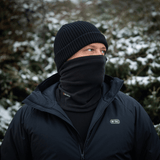 Mand iført M-Tac Tube Scarf Polartec i sneklædt landskab, beskyttet mod kulde med multifunktionel halstørklæde og jakke.