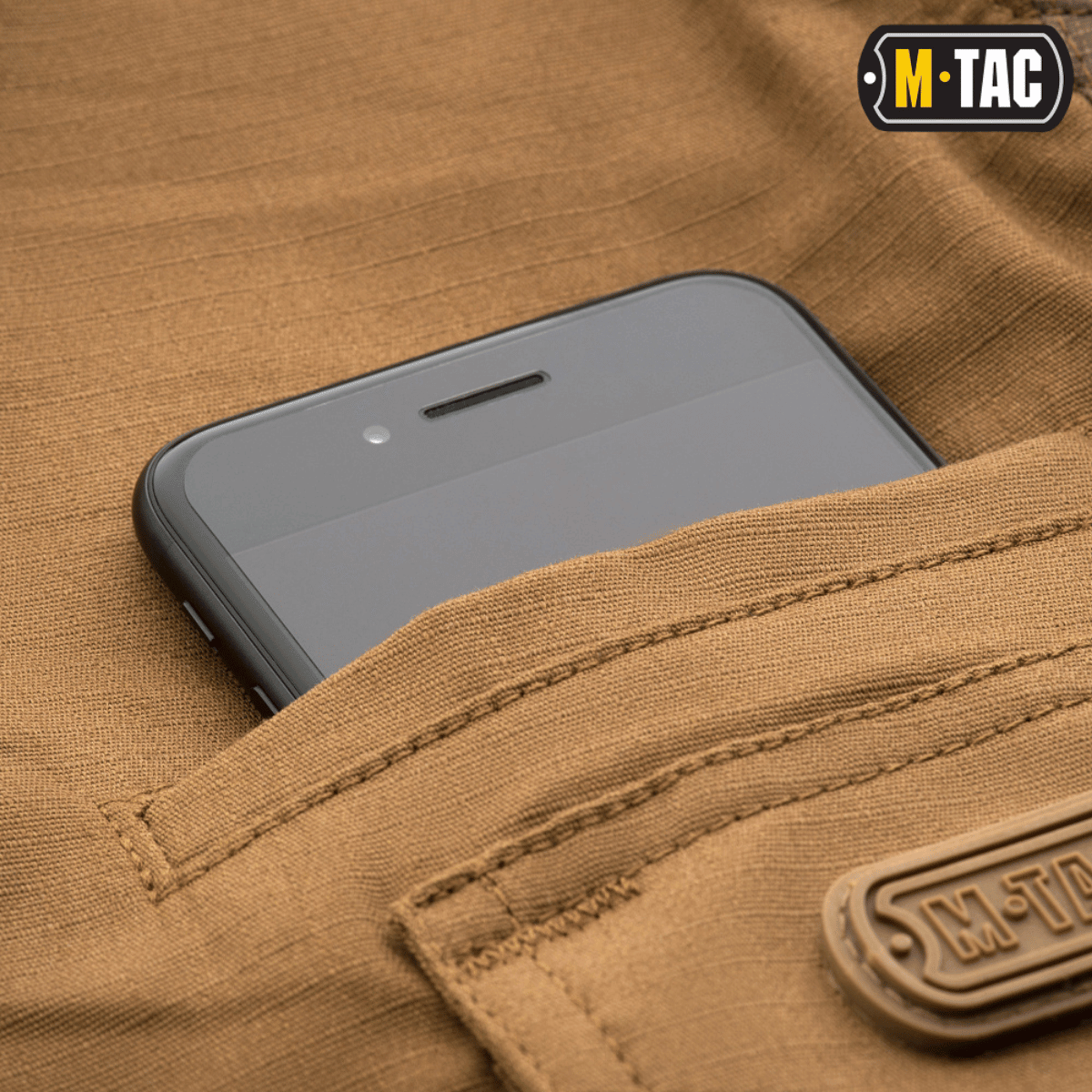 M-Tac Taktiske Bukser Aggressor Gen. II Flex med smartphone i lommen, lavet af let rip-stop stof med Teflon-belægning.