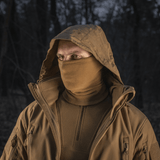 Person iført M-Tac Tube Scarf Polartec som ansigtsmaske i en skov om natten, beskyttet mod kulde og vind. Ideel til udendørs aktiviteter.